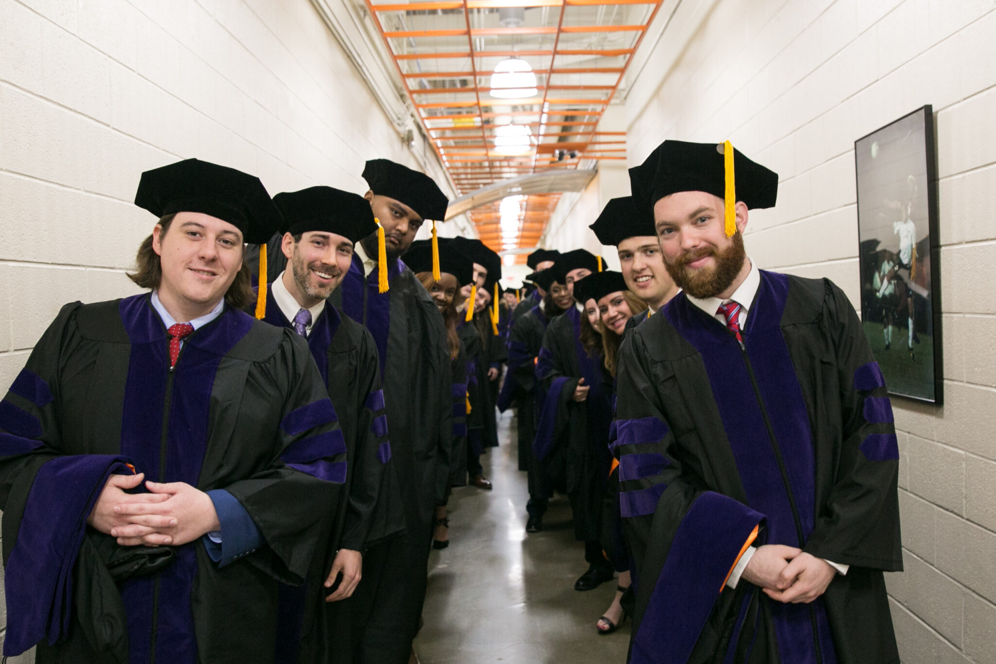 Group of students in a hallway, wearing graduation regalia