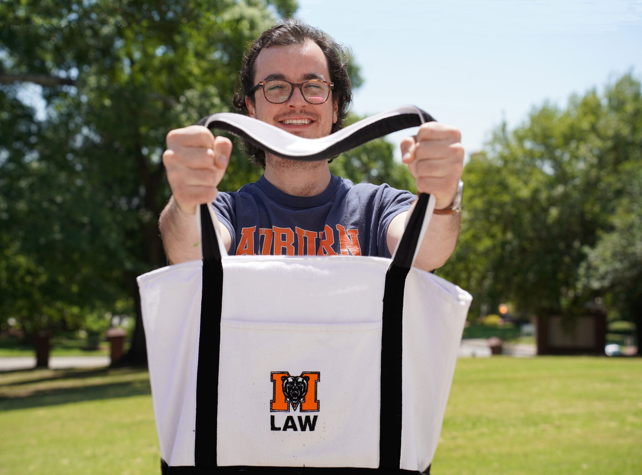 Male student holding a Mercer Law tote bag