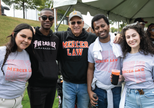 Four students and a professor outside, wearing Mercer Law shirts