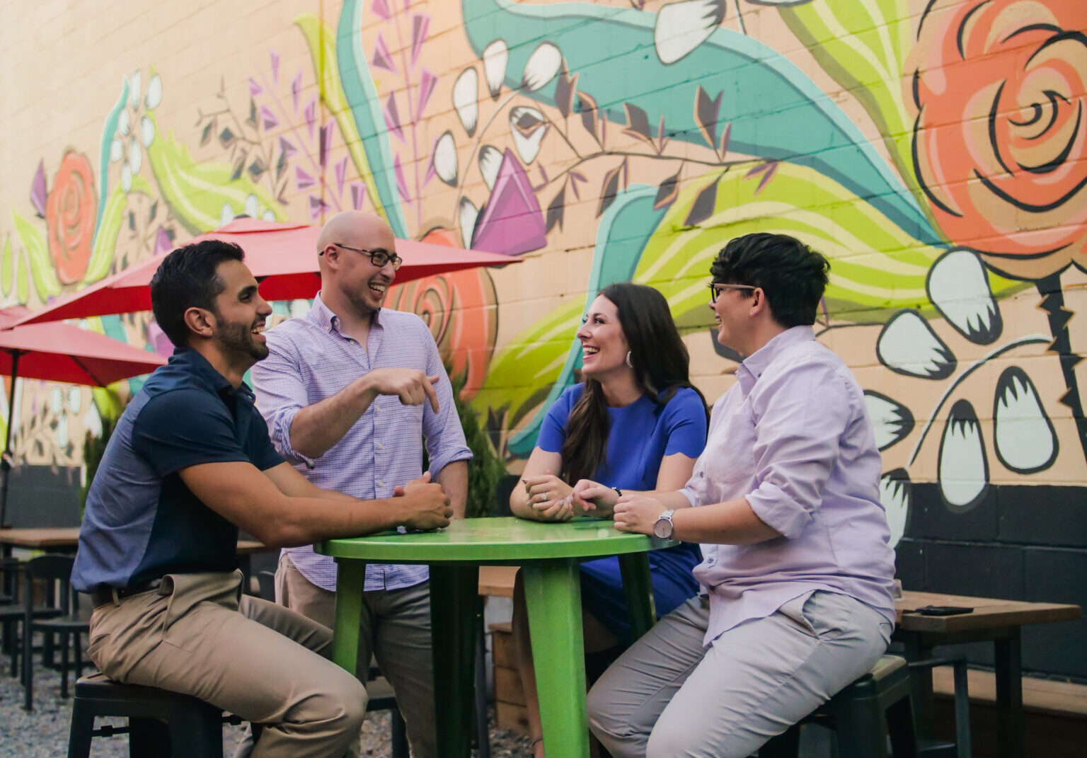 Four people laughing at an outdoor table