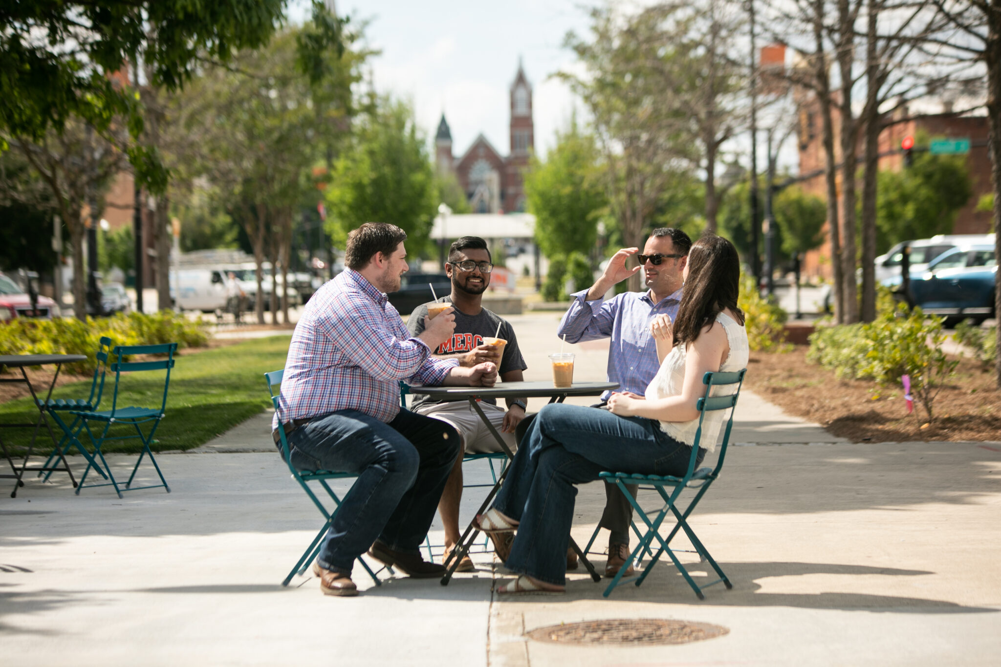 Three men and one woman sitting at a table outside in downtown Macon