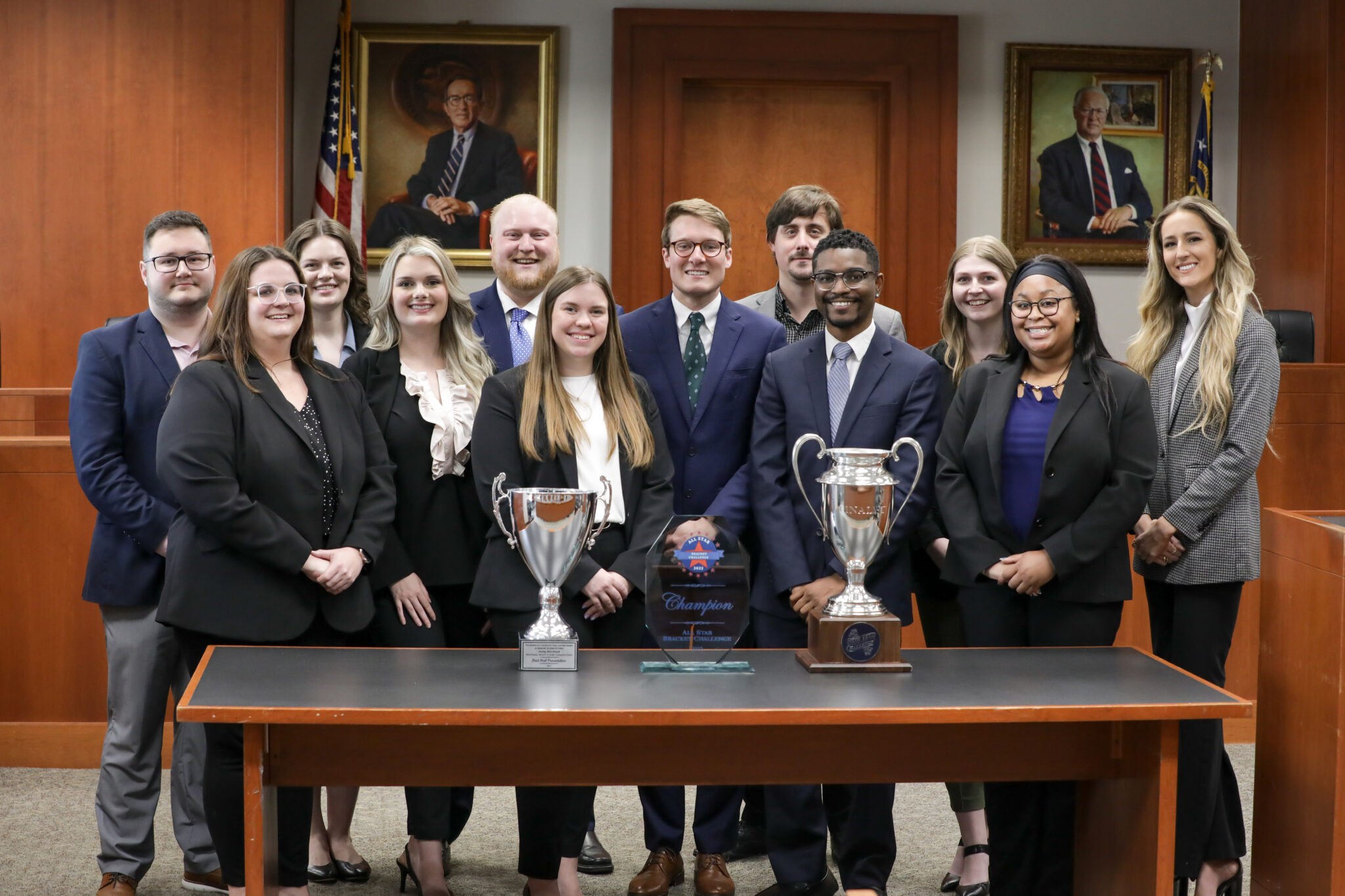 Group of students standing behind an array of trophies