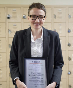 Professor Bonnie Carlson holding a faculty award plaque