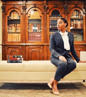 Sola Campbell sitting on a bench in front of a bookshelf