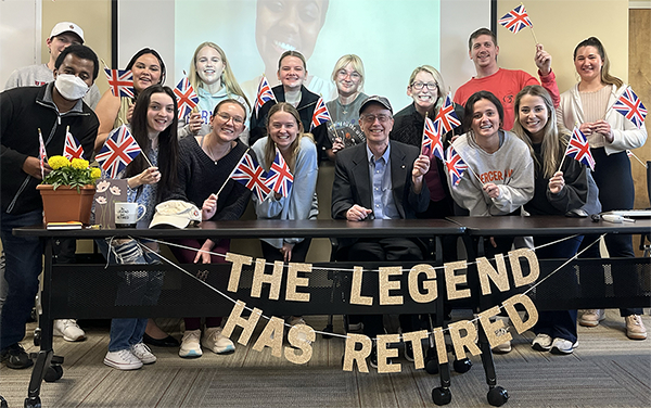 Students and Professor Mark Jones hold British flags behind a sign that reads 