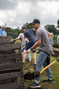 Law students using shovels to compost at the gardens at Brookdale Resource Center