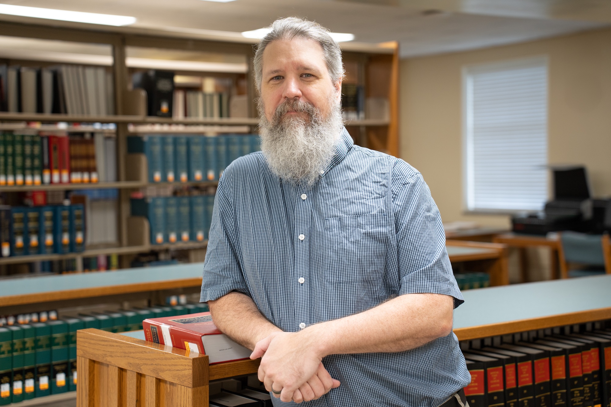 Chris Osier leaning against a bookshelf in the library