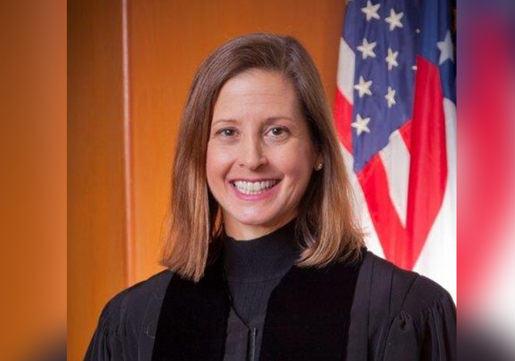 Sara Doyle in a black robe stands in front of an American flag