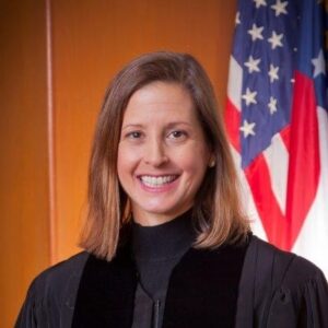 Sara Doyle in a black robe stands in front of an American flag