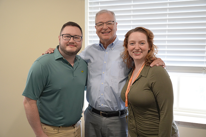 Walker Lee, John Carbo, and Lauren James standing in front of a window