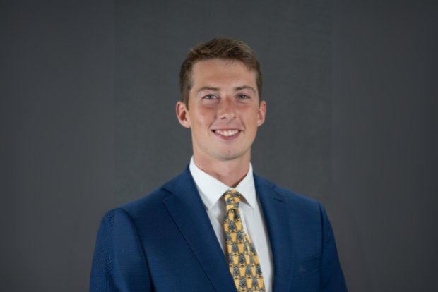 CJ Stiles stands in a blue suit in front of a gray background