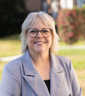 Julie Barnes in a gray jacket standing outside in front of a brick building