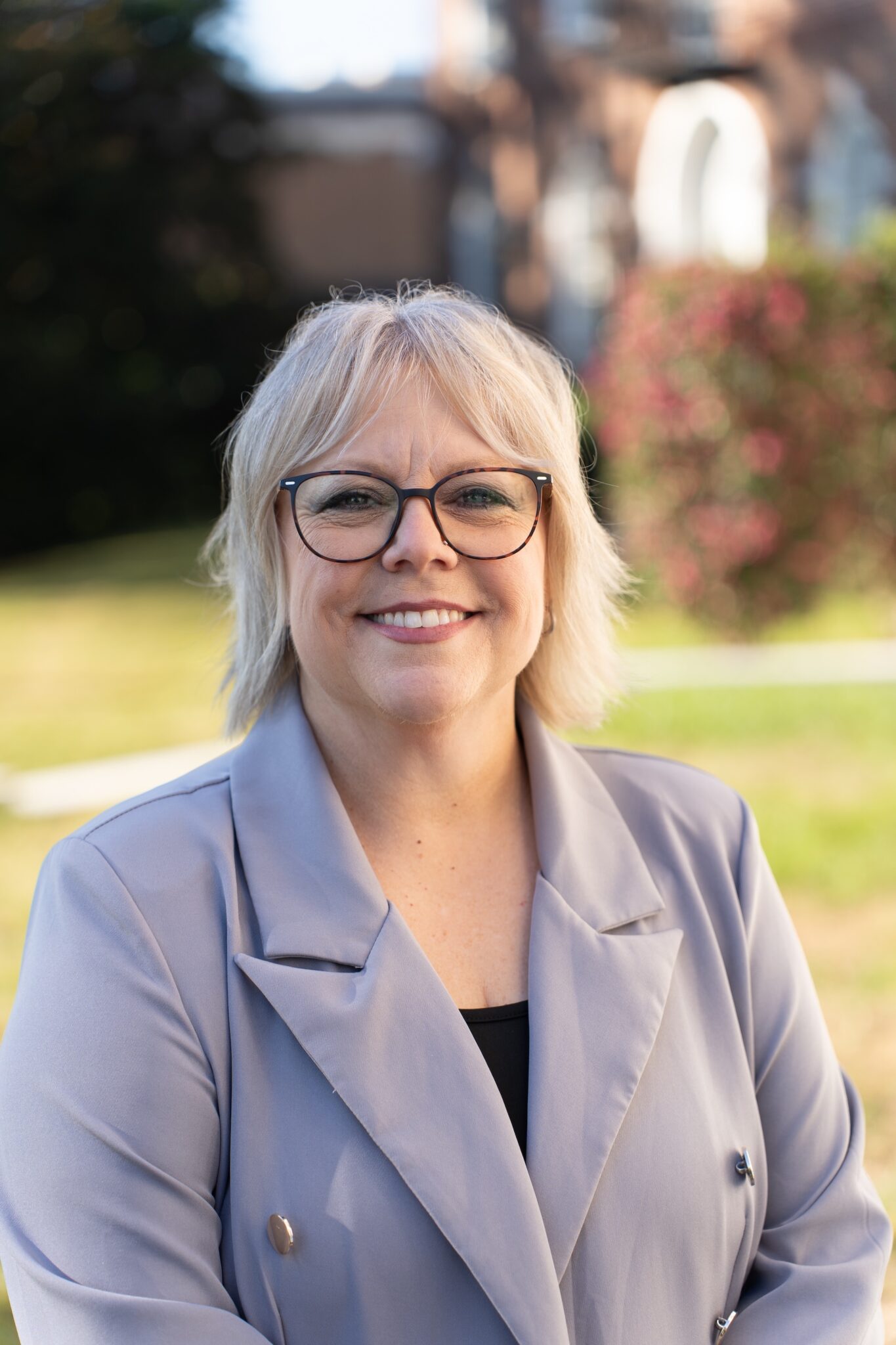 Julie Barnes in a gray jacket standing outside in front of a brick building