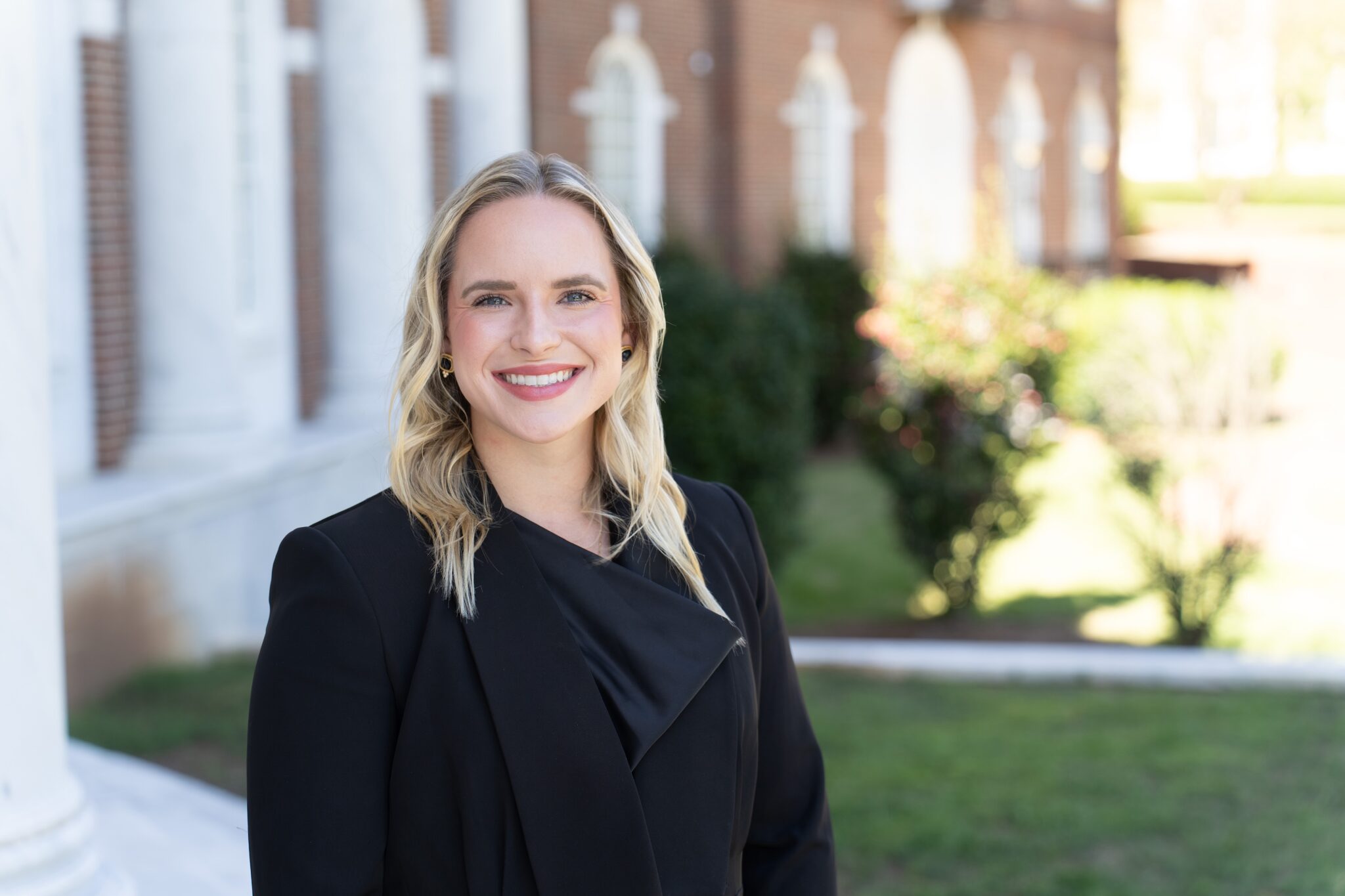 Caroline Hager stands on the front porch of the law school in a black blazer