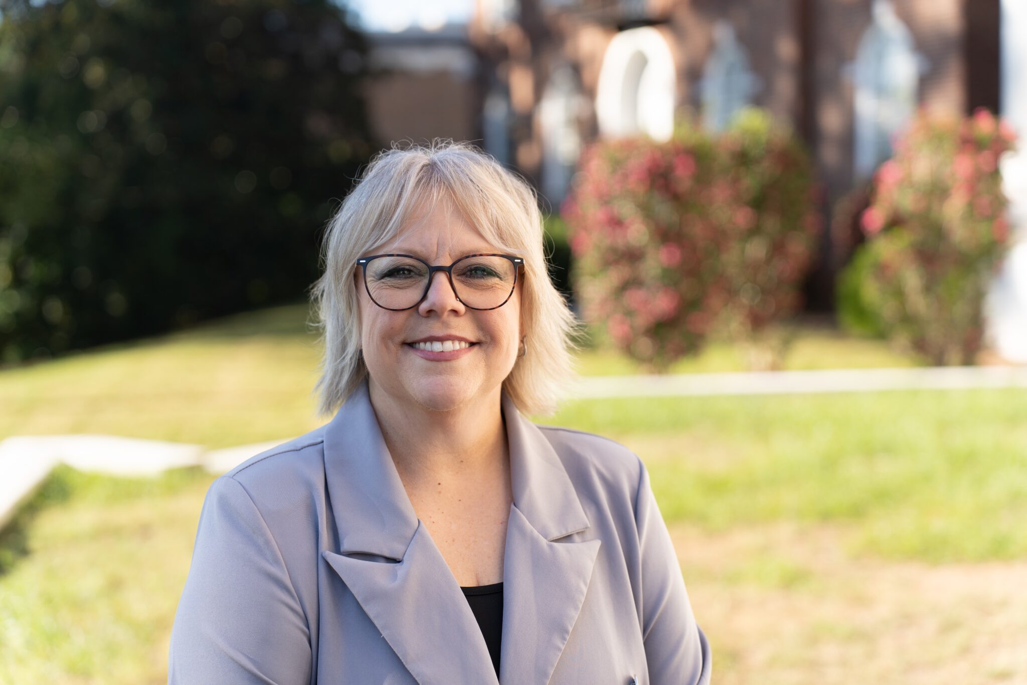 Julie Barnes in a gray jacket standing outside in front of a brick building