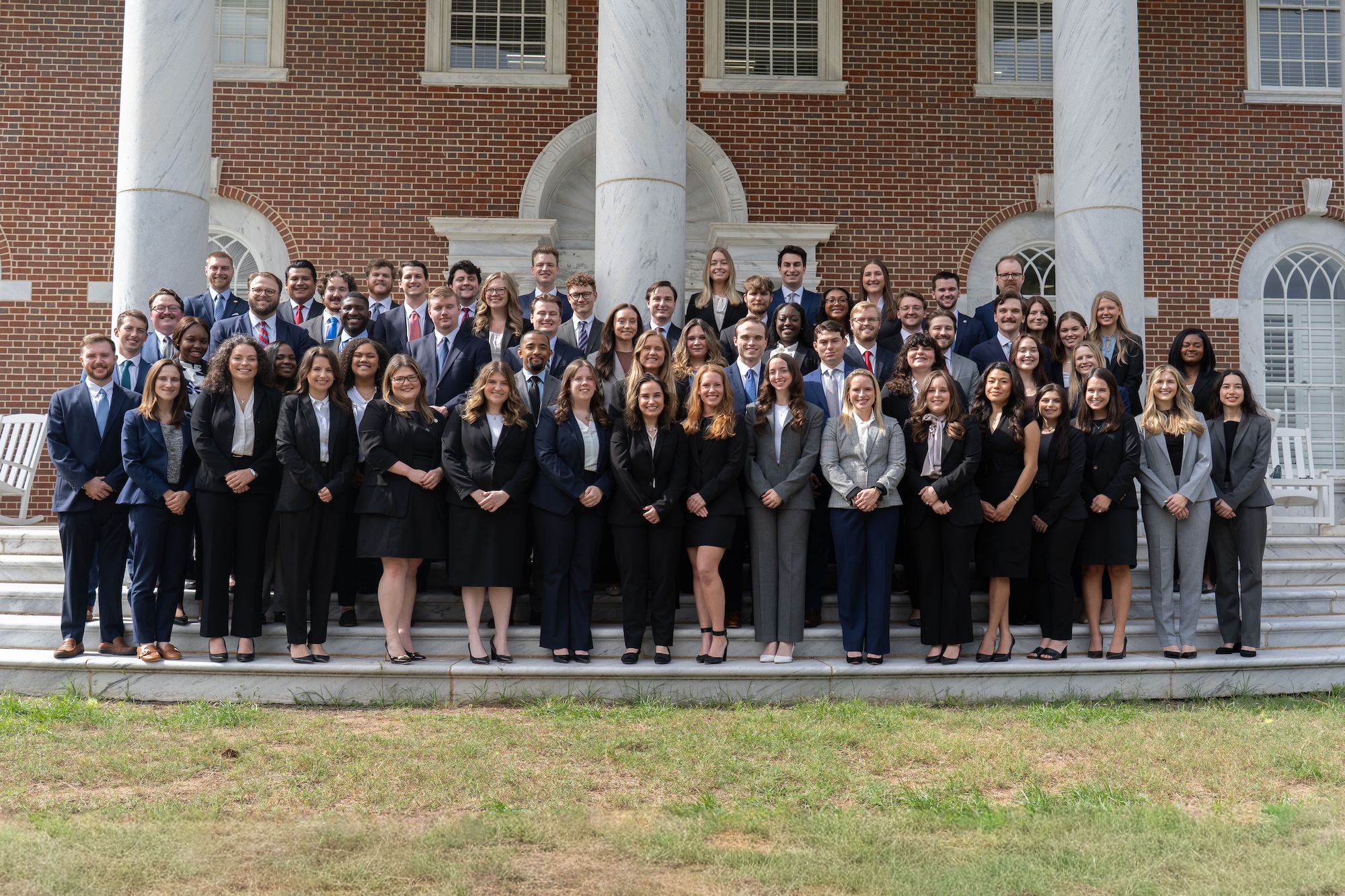 A large group of people in suits standing on the front porch of the law school