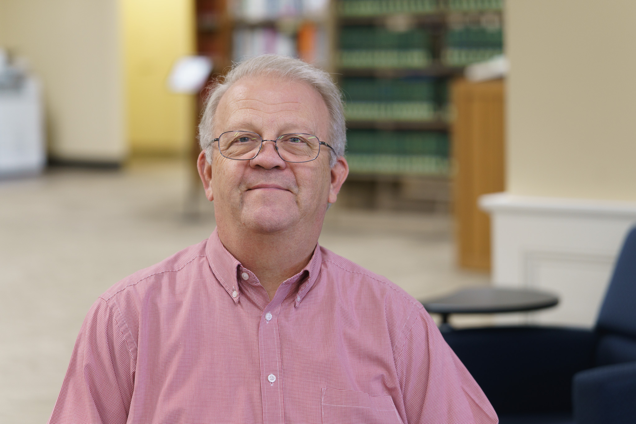 Steve Lindsey sits in the library in a red shirt