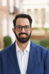 David Seibel stands outside in a blue jacket and white shirt