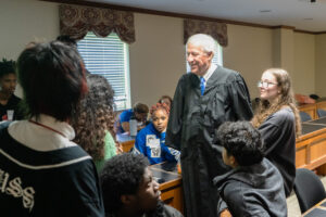 Judge Story stands with several students in a mock courtroom