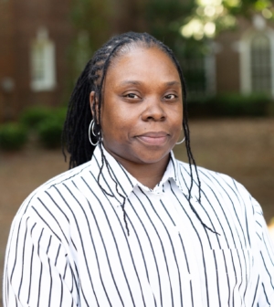 Amethia Dandy stands in a white and black striped shirt outside the law school