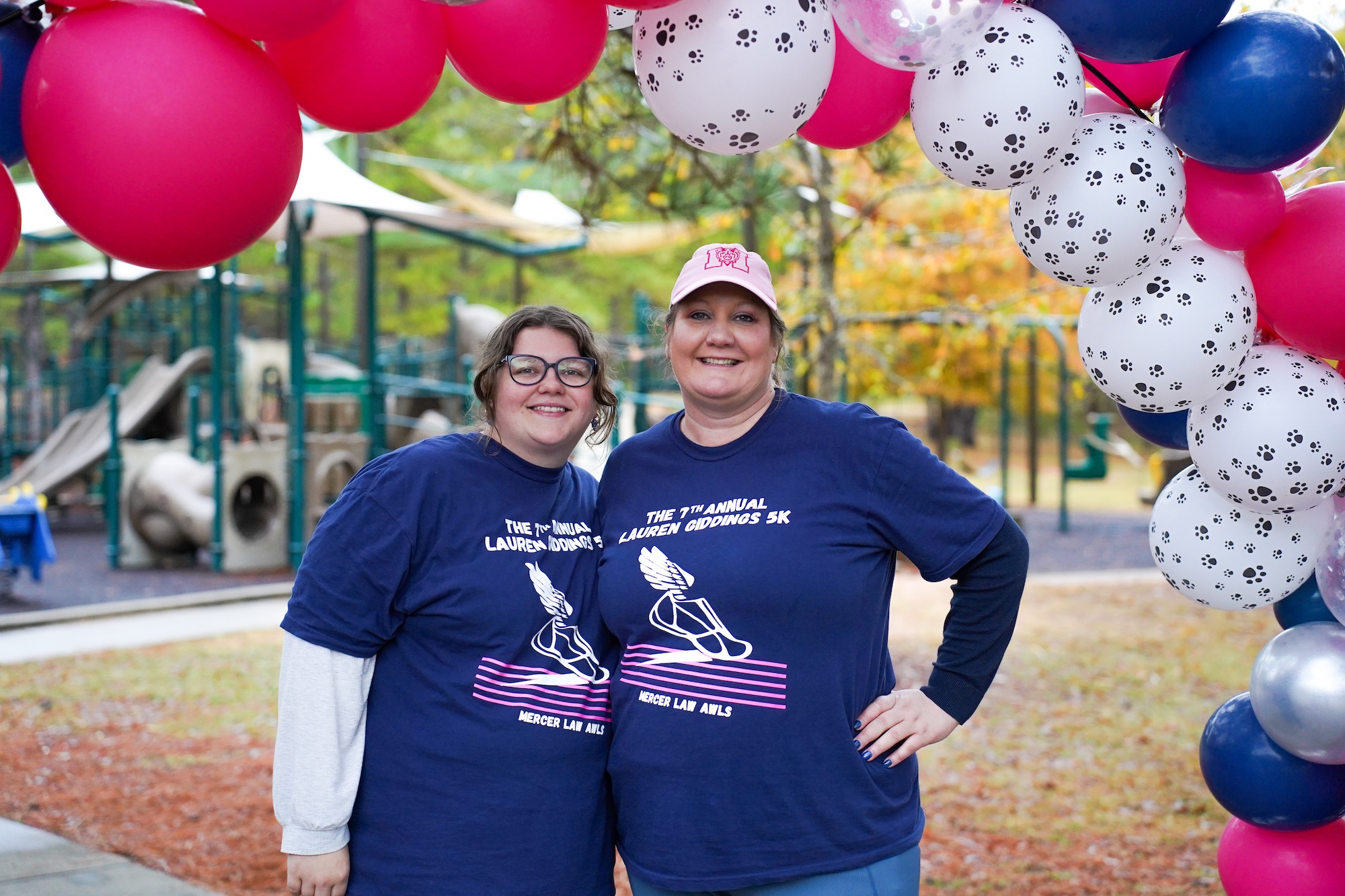 Two students stand under a balloon arch