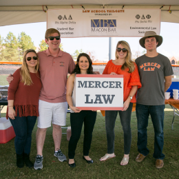 Five people standing under a tent with a sign that reads "Mercer Law"